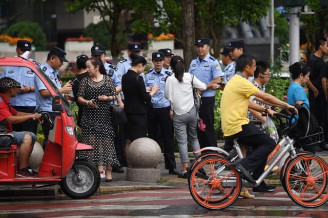 La policía comprueba la identificación de los transeúntes mientras busca a demandantes cerca de la Comisión Reguladora Bancaria de China en Beijing, el 6 de agosto de 2018. (Greg Baker/AFP a través de Getty Images)