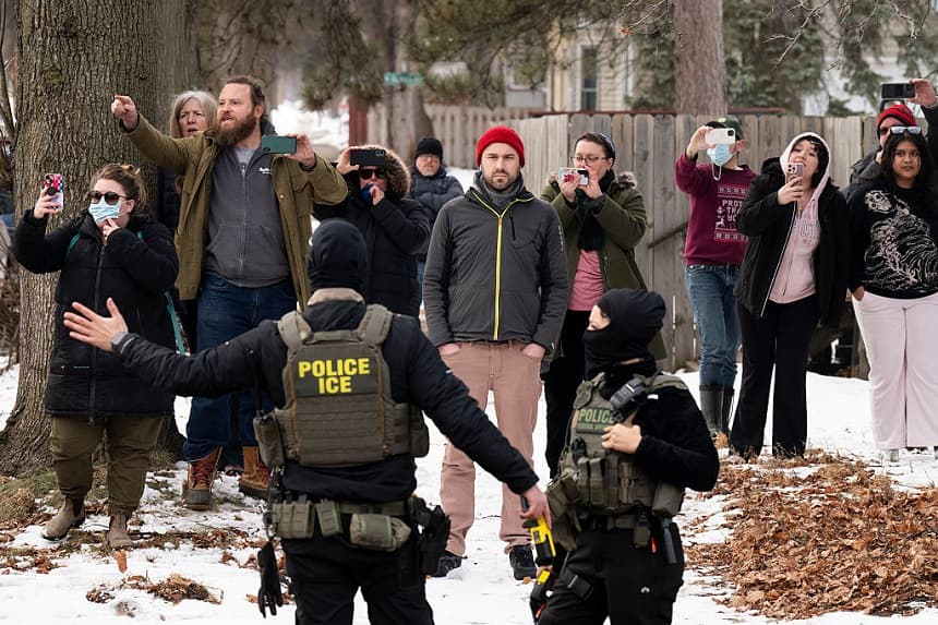 Observadores graban a agentes del ICE mientras mantienen un perímetro de seguridad después de que uno de sus vehículos sufriera un pinchazo en Penn Avenue el 5 de febrero de 2026 en Minneapolis, Minnesota. (Stephen Maturen/Getty Images)
