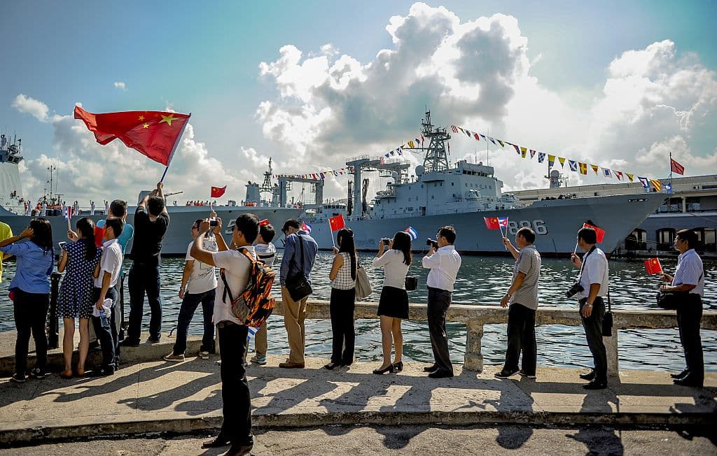 Personas ondean banderas cubanas y de la República Popular China mientras varios buques de la Armada china ingresan al puerto de La Habana el 10 de noviembre de 2015. (YAMIL LAGE/AFP vía Getty Images)