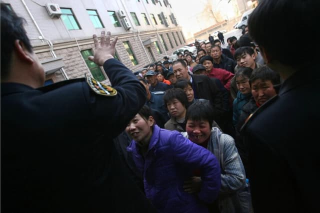 Funcionarios de la Oficina de Trabajo y Seguridad Social de Beijing instan a los trabajadores migrantes a reclamar los salarios que se les adeudan, el 9 de febrero de 2007 en Beijing, China. (China Photos/Getty Images)
