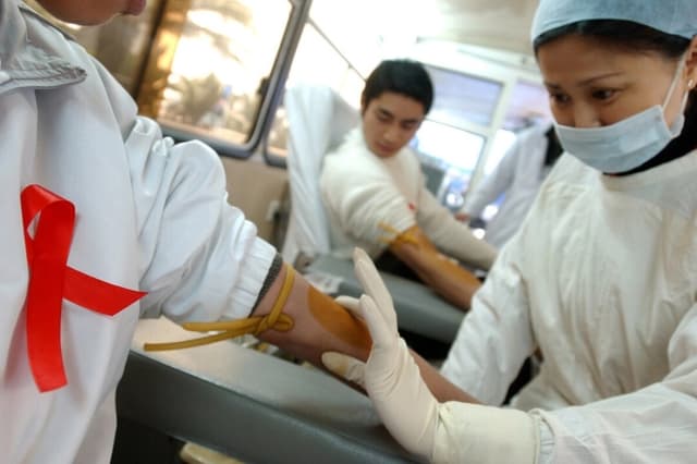 Una enfermera se prepara para extraer sangre de un donante durante una campaña de donación de sangre voluntaria para conmemorar el Día Mundial del SIDA, en Chengdu, provincia de Sichuan, suroeste de China, el 1 de diciembre de 2005. (China Photos/Getty Images)
