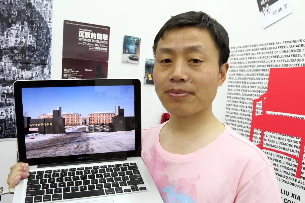 Du Bin sostiene una computadora portátil que muestra la puerta del Campo de Trabajos Forzados de Masanjia en un evento en Hong Kong el 27 de abril de 2013. Pan Zaishu/The Epoch Times