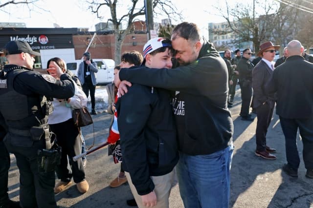 Un padre abraza a su hijo afuera del Lynch Arena en Pawtucket, RI, después de un tiroteo en la pista de hielo, el 16 de febrero de 2026. (Mark Stockwell/AP Photo)