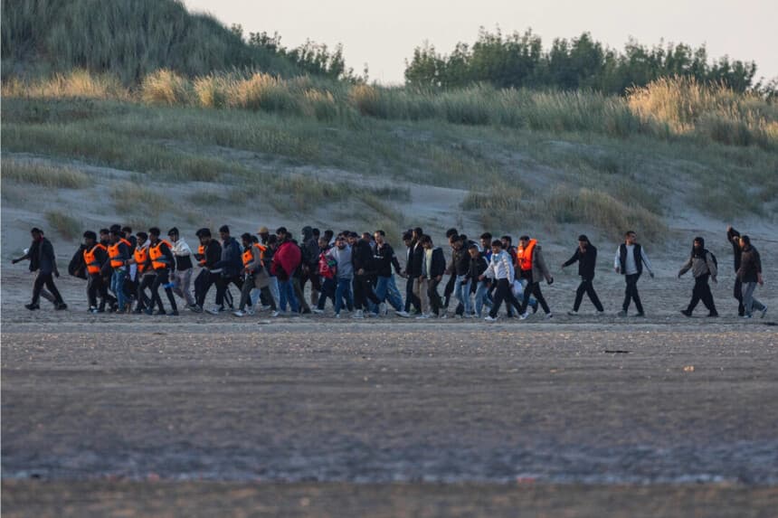 Migrantes caminan por la playa para esperar a que el barco de un contrabandista intente cruzar el Canal de la Mancha frente a la playa de Gravelines, en el norte de Francia, el 11 de agosto de 2025. (Sameer Al-Doumy/AFP vía Getty Images)