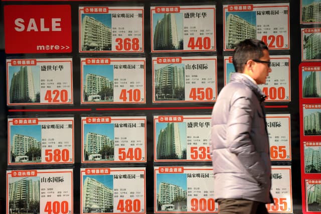 Un hombre caminando frente al escaparate de una agencia inmobiliaria en Shanghái, China, el 4 de diciembre de 2012. (Peter Parks/AFP vía Getty Images).