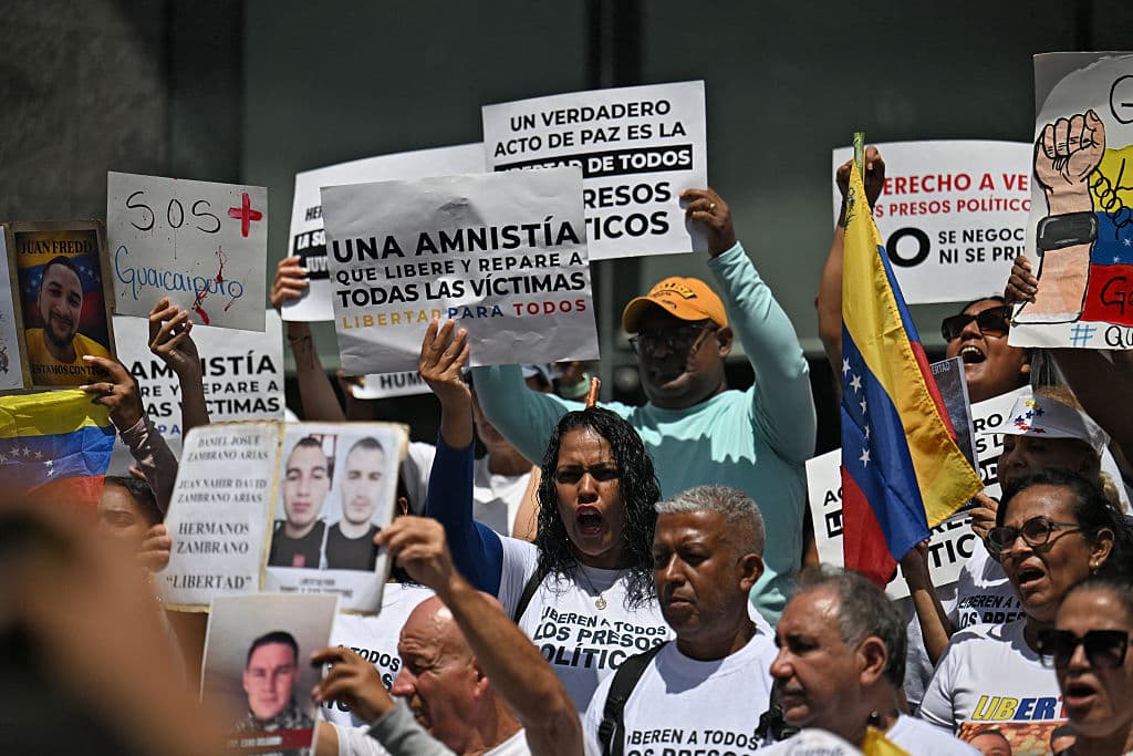 Familiares de presos políticos sostienen carteles y retratos de sus seres queridos frente a la sede de las Naciones Unidas en Caracas, el 18 de febrero de 2026, mientras el Congreso venezolano considera una ley de amnistía a los presos políticos, tras varios aplazamientos, entre huelgas de hambre, una de ellas en su día 5. (Foto de Juan BARRETO / AFP vía Getty Images)
