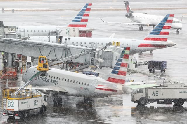 El personal de tierra descongela un avión de pasajeros Embraer ERJ-175 American Eagle en el aeropuerto LaGuardia de Nueva York el 22 de febrero de 2026. (Foto de CHARLY TRIBALLEAU / AFP a través de Getty Images)