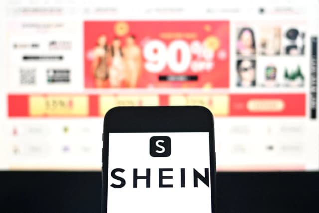 El logotipo de la empresa de comercio electrónico de moda Shein se muestra en un teléfono inteligente con la página web de la empresa al fondo en una foto tomada en Bangkok, el 6 de diciembre de 2024. (Manan Vatsyayana/AFP vía Getty Images)
