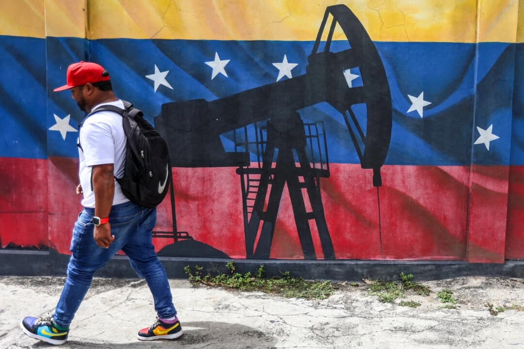Un hombre pasa junto a un mural que representa una bomba de aceite sobre una bandera venezolana, en Caracas, Venezuela, el 15 de enero de 2026. (Pedro Mattey/AFP vía Getty Images)