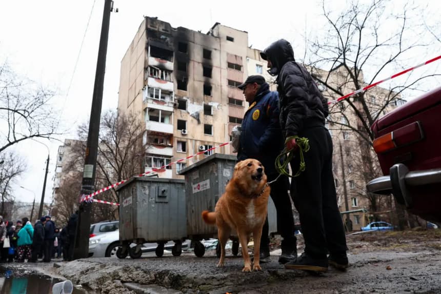Residentes locales pasean a un perro cerca de un edificio de apartamentos dañado por un dron ruso en Zaporizhzhia, Ucrania, el 26 de febrero de 2026. (AP Photo/Kateryna Klochko)