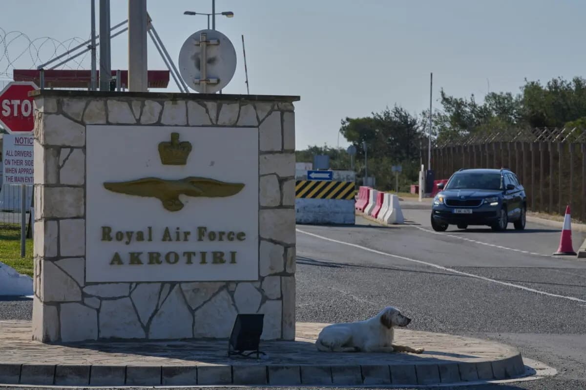 Un perro se sienta en la puerta principal de la base aérea británica RAF Akrotiri después de que fuera alcanzada por un ataque con drones cerca de Limassol, Chipre, el 2 de marzo de 2026. (Petros Karadjias/AP)
