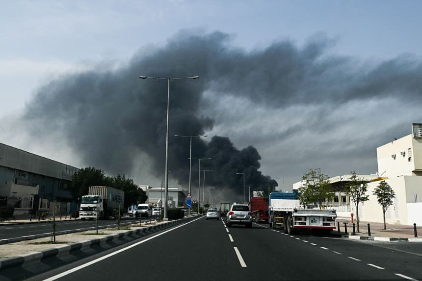 Automovilistas pasan junto a una columna de humo que se eleva tras un supuesto ataque iraní en el distrito industrial de Doha, el 1 de marzo de 2026. (Mahmud HAMS/AFP vía Getty Images)