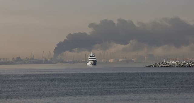 Un yate navega junto a una columna de humo que se eleva desde el puerto de Jebel Ali tras un supuesto ataque iraní en Dubái, el 1 de marzo de 2026. (Fadel SENNA/AFP vía Getty Images)