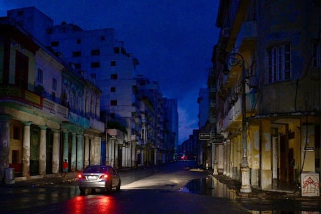 Un automóvil circula por una calle durante un apagón nacional causado por un fallo en la red eléctrica en La Habana, el 19 de octubre de 2024. Las averías técnicas, la escasez de combustible y la alta demanda han provocado fallos constantes en las centrales termoeléctricas del país, lo que ha obligado al Gobierno a declarar una emergencia energética y a tomar medidas como el cierre de colegios y fábricas. (ADALBERTO ROQUE/AFP vía Getty Images).