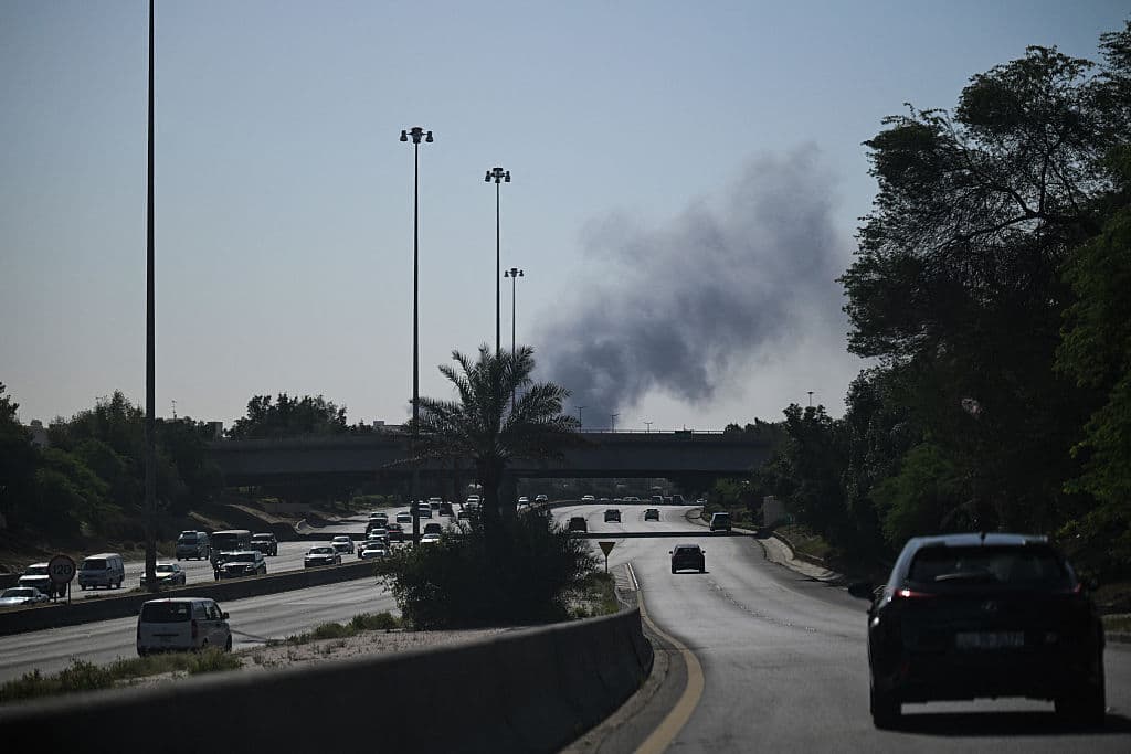 Conductores circulan por una calle mientras el humo se eleva tras un supuesto ataque iraní en la zona donde se encuentra la embajada de Estados Unidos en la ciudad de Kuwait, el 2 de marzo de 2026. (Foto de AFP vía Getty Images)