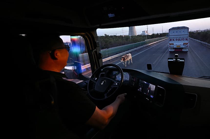 Esta fotografía, tomada el 13 de agosto de 2025, muestra a un conductor supervisando una prueba de un camión autónomo de la empresa de logística de conducción autónoma KargoBot en Ordos, en la región de Mongolia Interior, al norte de China. (PEDRO PARDO/AFP a través de Getty Images)
