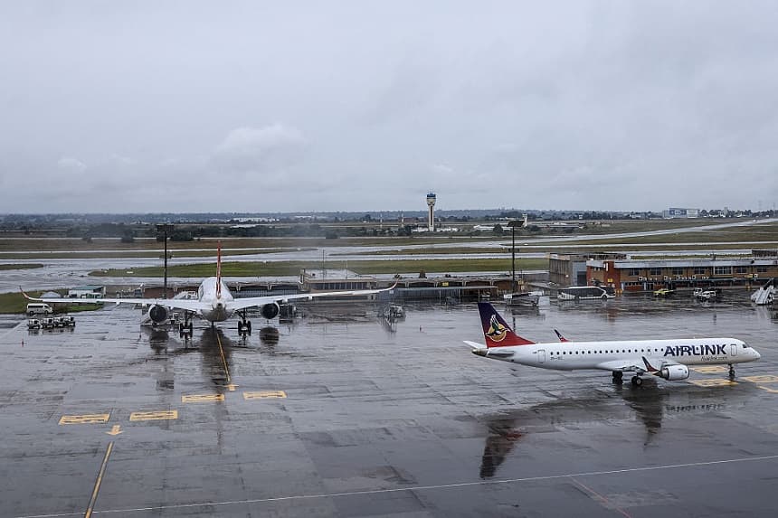 El avión E195 de South African Airlink (derecha) rueda por la pista mientras otro está estacionado tras aterrizar en el Aeropuerto Internacional OR Tambo de Ekurhuleni el 12 de marzo de 2026. (Phill Magakoe / AFP a través de Getty Images)