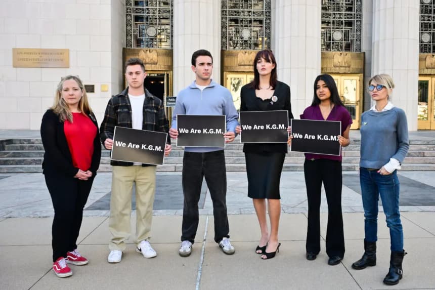 Los seguidores de "K.G.M." posan con carteles frente a la Corte Superior de Los Ángeles el 25 de febrero de 2026, durante el juicio sobre las redes sociales para determinar si las plataformas fueron diseñadas deliberadamente para crear adicción en los niños. (Frederic J. Brown/AFP vía Getty Images)