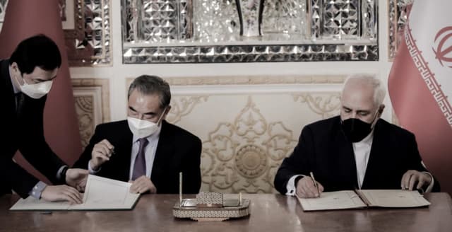 El ministro de Asuntos Exteriores iraní, Mohammad Javad Zarif (derecha), y su homólogo chino, Wang Yi (centro), firman un acuerdo en la capital, Teherán, Irán, el 27 de marzo de 2021. (AFP vía Getty Images)