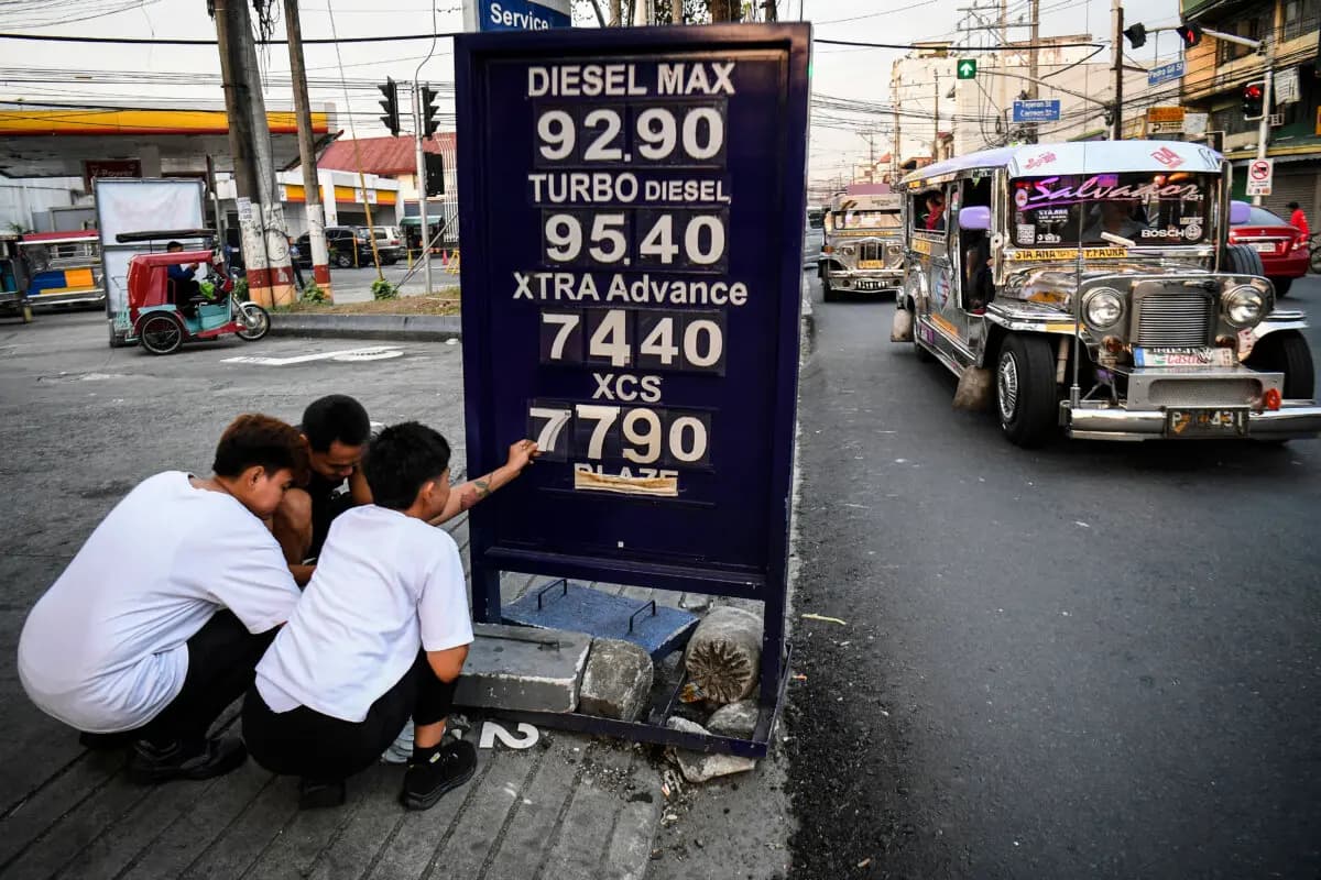Unos trabajadores cambian la etiqueta del precio del combustible en una gasolinera de Manila, Filipinas, el 17 de marzo de 2026. El precio del petróleo volvió a subir en Asia el 17 de marzo, tras el retroceso registrado el día anterior, mientras los inversores seguían centrados en el estrecho de Ormuz. (Ted Aljibe/AFP vía Getty Images).
