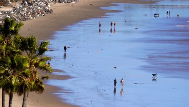 Varias personas caminan por una playa en Malibú, California, el 23 de marzo de 2020. (Foto de Mark J. Terrill/AP).