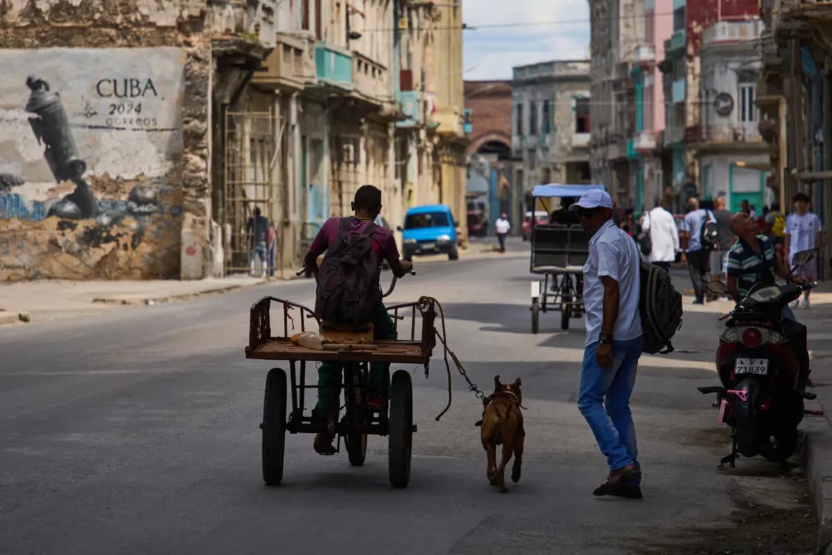 Un hombre monta en triciclo con su perro atado con una correa corriendo a su lado durante un apagón en La Habana, Cuba, el 16 de marzo de 2026. (Ramón Espinosa/Foto de AP)