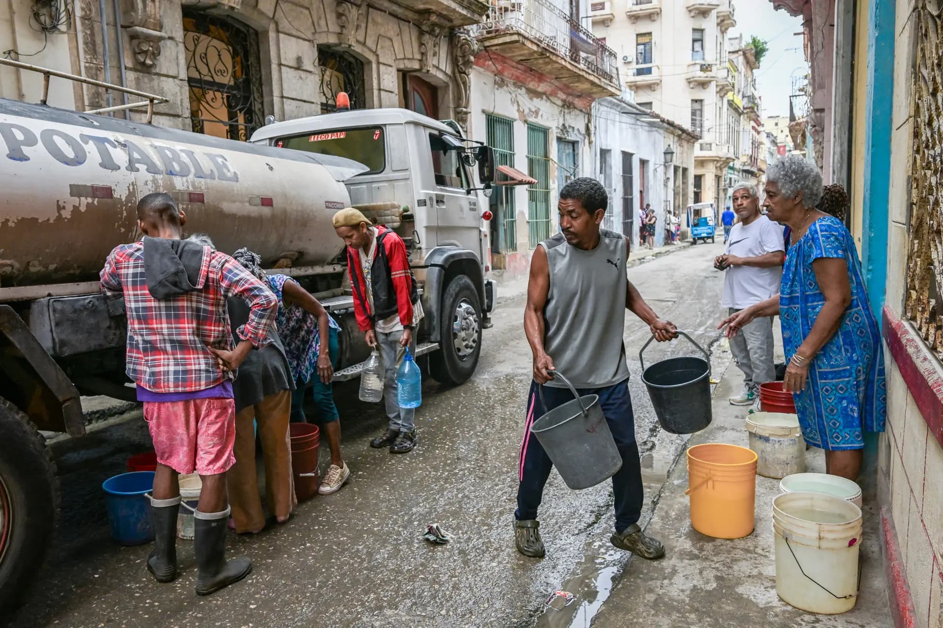 Varias personas esperan para llenar sus bidones y cubos desde un camión cisterna en La Habana, el 20 de marzo de 2026. Yamil Lage/AFP vía Getty Images

