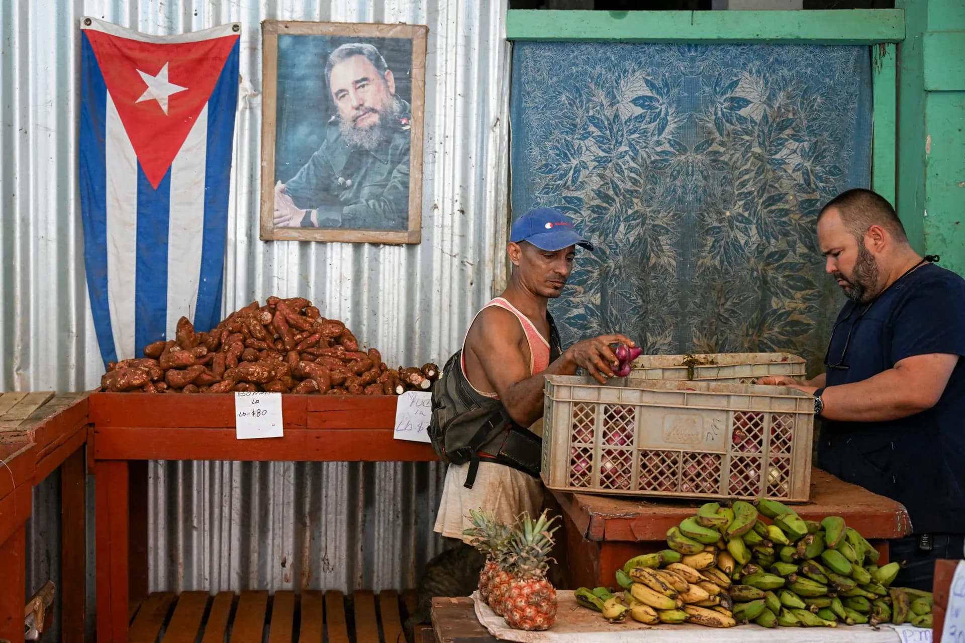 Un vendedor de comida organiza su puesto decorado con un cartel del fallecido líder cubano Fidel Castro y una bandera nacional en La Habana, el 13 de marzo de 2026. (Yamil Lage/AFP vía Getty Images)