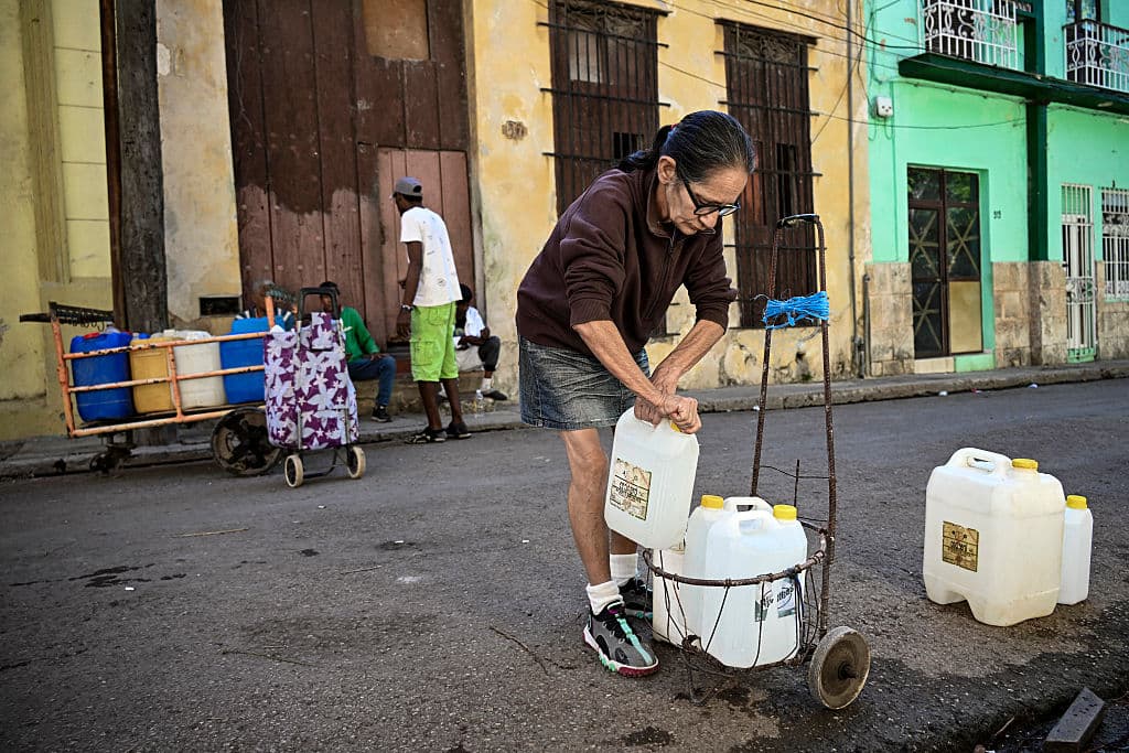 Una mujer prepara su carrito tras llenar sus bidones de agua en La Habana durante un apagón nacional el 22 de marzo de 2026. Las autoridades cubanas se apresuraron ese día a restablecer el suministro eléctrico en la isla tras el segundo apagón nacional en menos de una semana, debido a las dificultades que atraviesa la red eléctrica por el envejecimiento de la infraestructura. (Foto de YAMIL LAGE / AFP vía Getty Images)