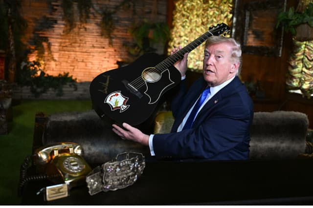 El presidente de Estados Unidos, Donald Trump, sostiene una réplica de una guitarra de Elvis Presley tras firmarla durante su visita a Graceland, la residencia de Presley, el 23 de marzo de 2026 en Memphis, Tennessee. El presidente Trump visitó Graceland tras participar en una mesa redonda del Grupo de Trabajo "Memphis Safe" sobre la lucha contra los delitos violentos. (Roberto Schmidt/Getty Images).