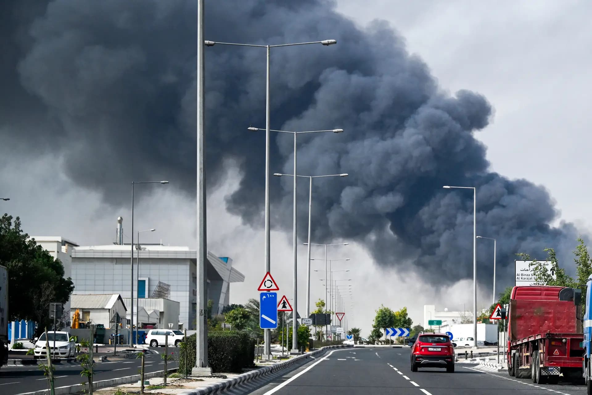 Los conductores pasan junto a una columna de humo que se eleva tras un supuesto ataque iraní en el distrito industrial de Doha, Catar, el 1 de marzo de 2026. (Mahmud Hams / AFP vía Getty Images).