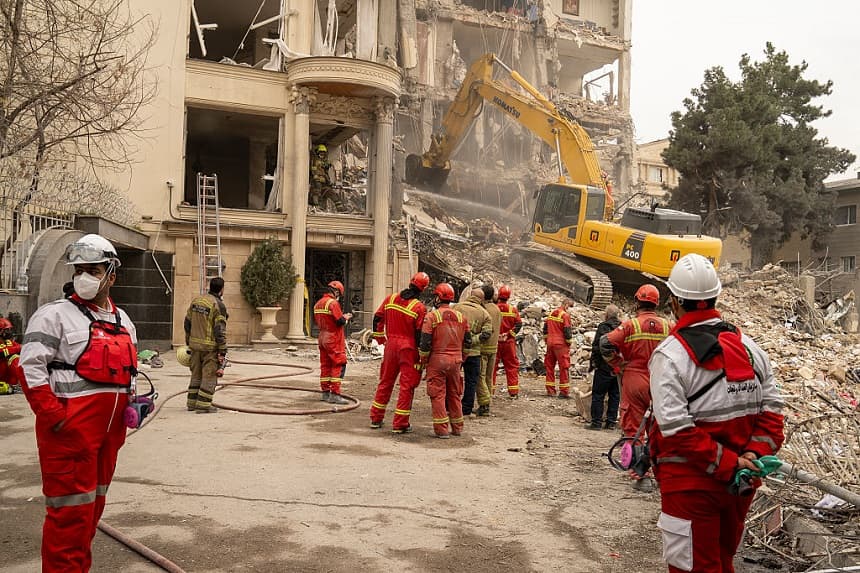 Los equipos de rescate, con ayuda de maquinaria pesada, retiran los escombros de un edificio residencial destruido el 23 de marzo de 2026 en el norte de Teherán, Irán. (Majid Saeedi/Getty Images)