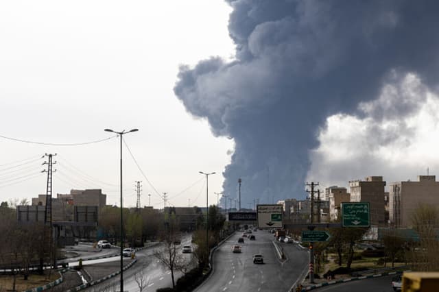 Varios automóviles circulan por una autopista mientras se elevan columnas de humo tras los ataques aéreos perpetrados durante la noche contra depósitos de petróleo el 8 de marzo de 2026 en Teherán, Irán. Estados Unidos e Israel continuaron con su ataque conjunto contra Irán, iniciado el 28 de febrero. Irán respondió lanzando oleadas de misiles y drones contra Israel y atacando a los aliados de Estados Unidos en la región. (Majid Saeedi/Getty Images).