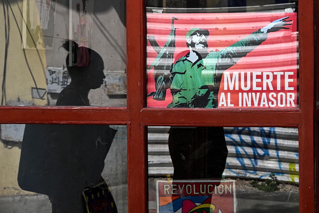 <em>Una persona pasa al lado de un cartel del líder cubano Fidel Castro con la inscripción "Muerte al invasor" en La Habana, el 13 de marzo de 2026. (Foto de YAMIL LAGE / AFP vía Getty Images)</em>