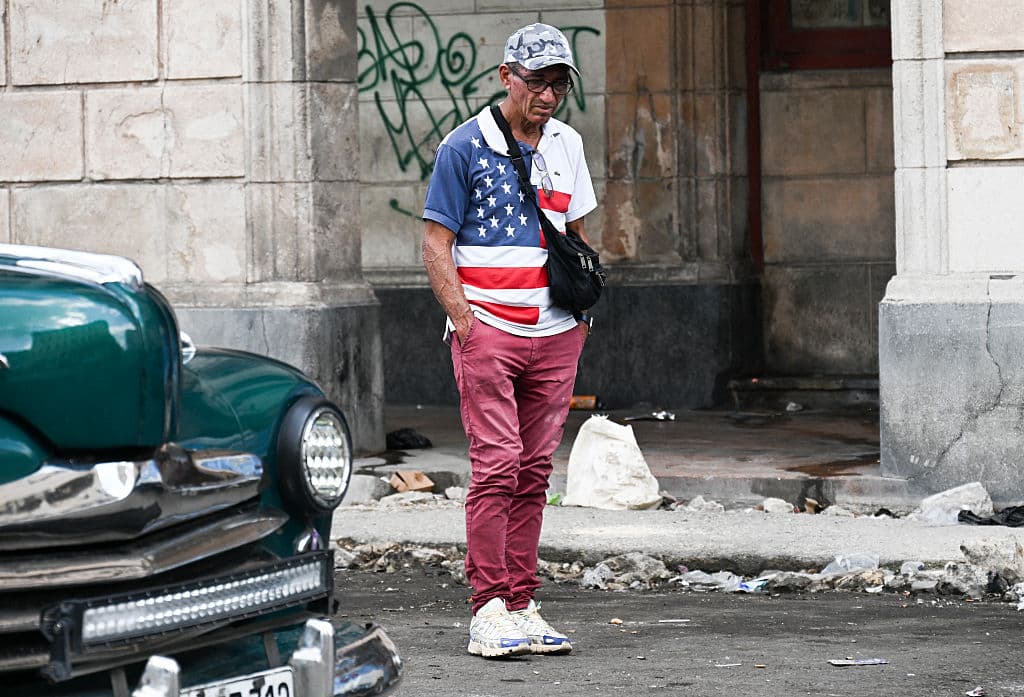<em>Un hombre con una camiseta con la bandera de Estados Unidos camina por una calle de La Habana el 13 de marzo de 2026. El presidente de Cuba, Miguel Díaz-Canel, confirmó ese mismo día que "funcionarios cubanos han mantenido conversaciones recientemente" con representantes de Estados Unidos, en medio de la creciente tensión entre Washington y La Habana. (Foto de YAMIL LAGE / AFP vía Getty Images)</em>