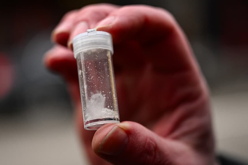 Un agente de la policía de Portland sostiene un frasco de metanfetamina hallado tras multar a una persona por consumo de drogas en el centro de Portland, Oregón, el 25 de enero de 2024. (PATRICK T. FALLON/AFP vía Getty Images)