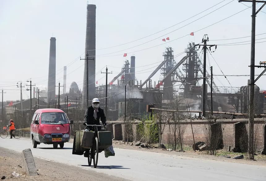 Un ciclista recorre una carretera polvorienta flanqueada por docenas de fábricas que procesan tierras raras, hierro y carbón, en las afueras de la ciudad de Baotou, en Mongolia Interior, al noroeste de China, el 21 de abril de 2011. (Frederic J. Brown/AFP/Getty Images)