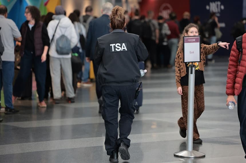 Un agente de la TSA pasa junto a los viajeros que esperan en fila para pasar el control de seguridad en la Terminal 8 del Aeropuerto Internacional John F. Kennedy el 27 de marzo de 2026 en Nueva York, Nueva York. (Michael M. Santiago/Getty Images)