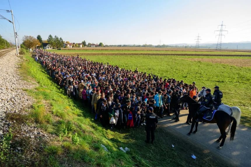 La policía escolta a los migrantes mientras caminan hacia un centro de refugiados tras cruzar la frontera entre Croacia y Eslovenia cerca de Rigonce, Eslovenia, el 24 de octubre de 2015. (Jure Makovec/AFP/Getty Images)
