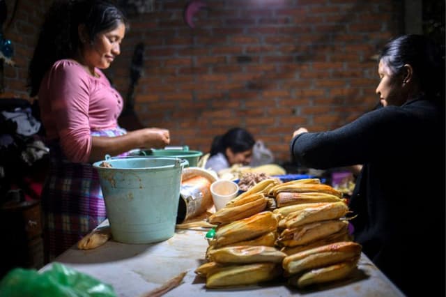 Un grupo de mujeres prepara tamales típicos para ofrecer a los visitantes que acuden a rezar y a velar las ofrendas en las casas durante la conmemoración del Día de los Muertos. (ENRIQUE CASTRO/AFP vía Getty Images)