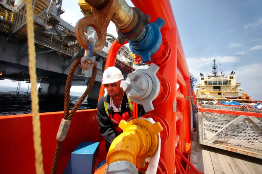 Un tripulante de un buque de suministro gira una válvula para transferir combustible a la plataforma de perforación Development Driller III frente a la costa de Luisiana, en el Golfo de México, el 11 de mayo de 2010. (Gerald Herbert-pool/Getty Images)