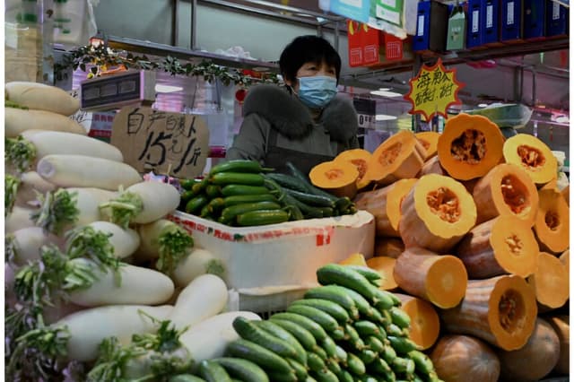 Un vendedor de verduras espera clientes en un mercado de Beijing el 17 de enero de 2022. (Noel Celis/AFP vía Getty) Images)
