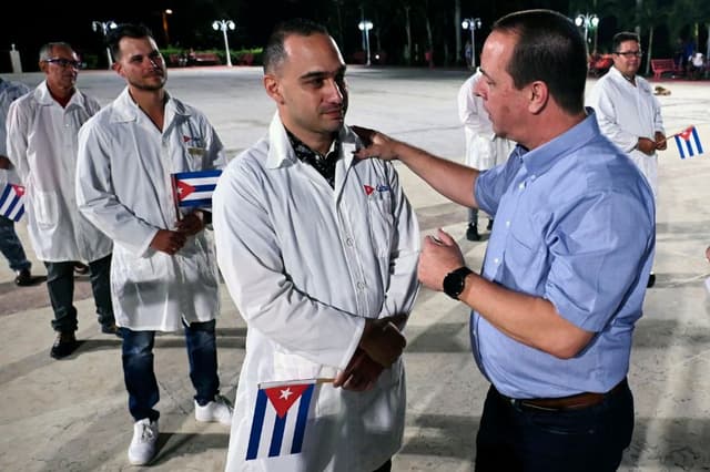 El ministro de Salud de Cuba, José Ángel Portal (a la derecha), saluda a los médicos y enfermeros de la Brigada Médica Internacional "Henry Reeve" de Cuba antes de que partan hacia Turquía para atender a las víctimas del terremoto, en la Unidad Central de Cooperación Médica de La Habana, el 10 de febrero de 2023. (YAMIL LAGE/AFP vía Getty Images)