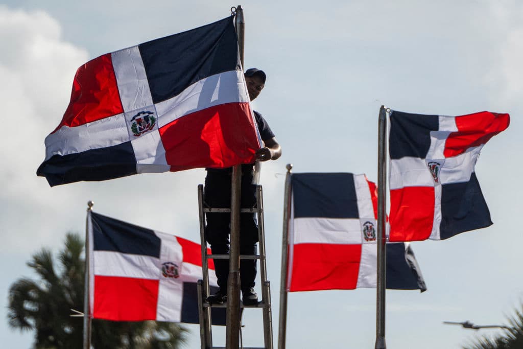 Un trabajador coloca banderas de la República Dominicana en mástiles durante los preparativos para la toma de posesión del presidente Abinader en Santo Domingo el 15 de agosto de 2024. El presidente dominicano Luis Abinader juró el cargo el 16 de agosto tras su reelección para el período 2024-2028. (Foto de FRANCESCO SPOTORNO/AFP vía Getty Images)