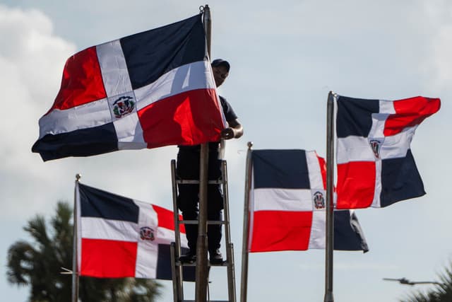 Un trabajador coloca banderas de la República Dominicana en mástiles durante los preparativos para la toma de posesión del presidente Abinader en Santo Domingo el 15 de agosto de 2024. El presidente dominicano Luis Abinader juró el cargo el 16 de agosto tras su reelección para el período 2024-2028. (Foto de FRANCESCO SPOTORNO/AFP vía Getty Images)