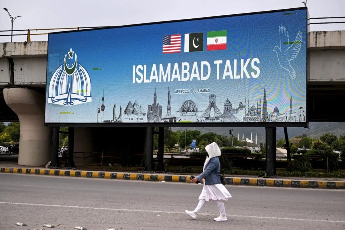 Una mujer pasa junto a una pantalla digital que muestra noticias sobre las conversaciones de paz entre Estados Unidos e Irán en una calle de Islamabad, Pakistán, el 10 de abril de 2026. (Farooq Naeem/AFP vía Getty Images)