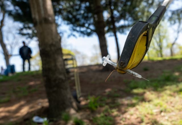 rabajadores de alcance comunitario de St. Ann’s Corner of Harm Reduction recolectan agujas sucias mientras participan en una limpieza semanal de jeringas en un parque del Bronx que los consumidores de drogas suelen utilizar, el 23 de abril de 2025 en la ciudad de Nueva York. (Spencer Platt/Getty Images)