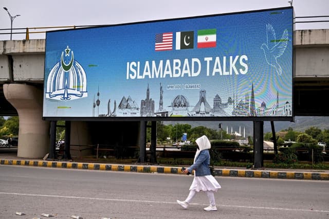 Una mujer pasa junto a una pantalla digital en la que se muestran noticias sobre las conversaciones de paz entre Estados Unidos e Irán, en una calle de Islamabad (Pakistán), el 10 de abril de 2026. (Farooq Naeem/AFP vía Getty Images).