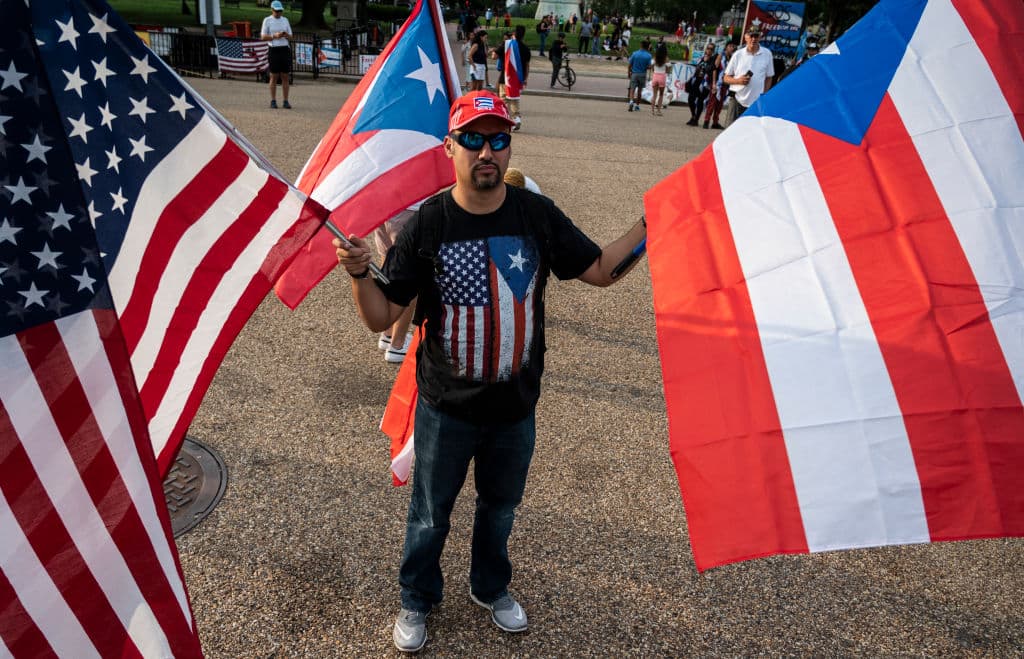 Un hombre sostiene banderas de Estados Unidos y Cuba durante una protesta en apoyo a los cubanos que se manifiestan contra su gobierno frente a la Casa Blanca en Washington, D.C., el 18 de julio de 2021. El presidente de Cuba, Miguel Díaz-Canel, denunció el 17 de julio lo que calificó de narrativa falsa sobre los disturbios en la isla caribeña, mientras el régimen comunista rechazaba la existencia de un descontento generalizado desde hace tiempo. (Foto de ANDREW CABALLERO-REYNOLDS/AFP vía Getty Images)