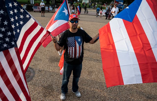 Un hombre sostiene banderas de Estados Unidos y Cuba durante una protesta en apoyo a los cubanos que se manifiestan contra su gobierno frente a la Casa Blanca en Washington, D.C., el 18 de julio de 2021. El presidente de Cuba, Miguel Díaz-Canel, denunció el 17 de julio lo que calificó de narrativa falsa sobre los disturbios en la isla caribeña, mientras el régimen comunista rechazaba la existencia de un descontento generalizado desde hace tiempo. (Foto de ANDREW CABALLERO-REYNOLDS/AFP vía Getty Images)